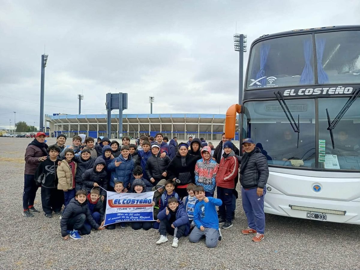 Delegación juvenil junto a una unidad de El Costeño frente a un estadio